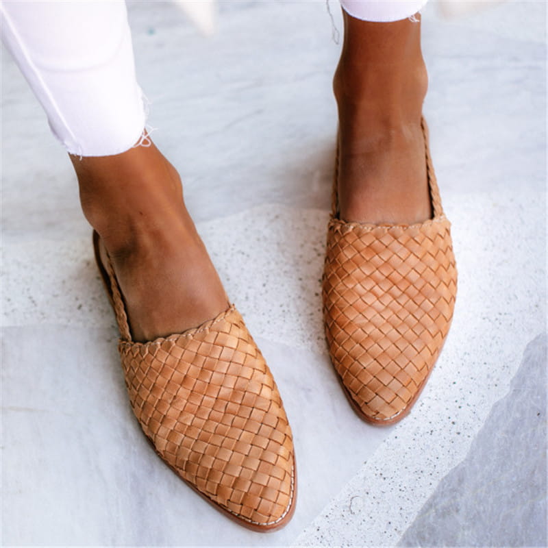 Tan woven leather mules with a pointed toe design and buckle detail in a flat sandal style.