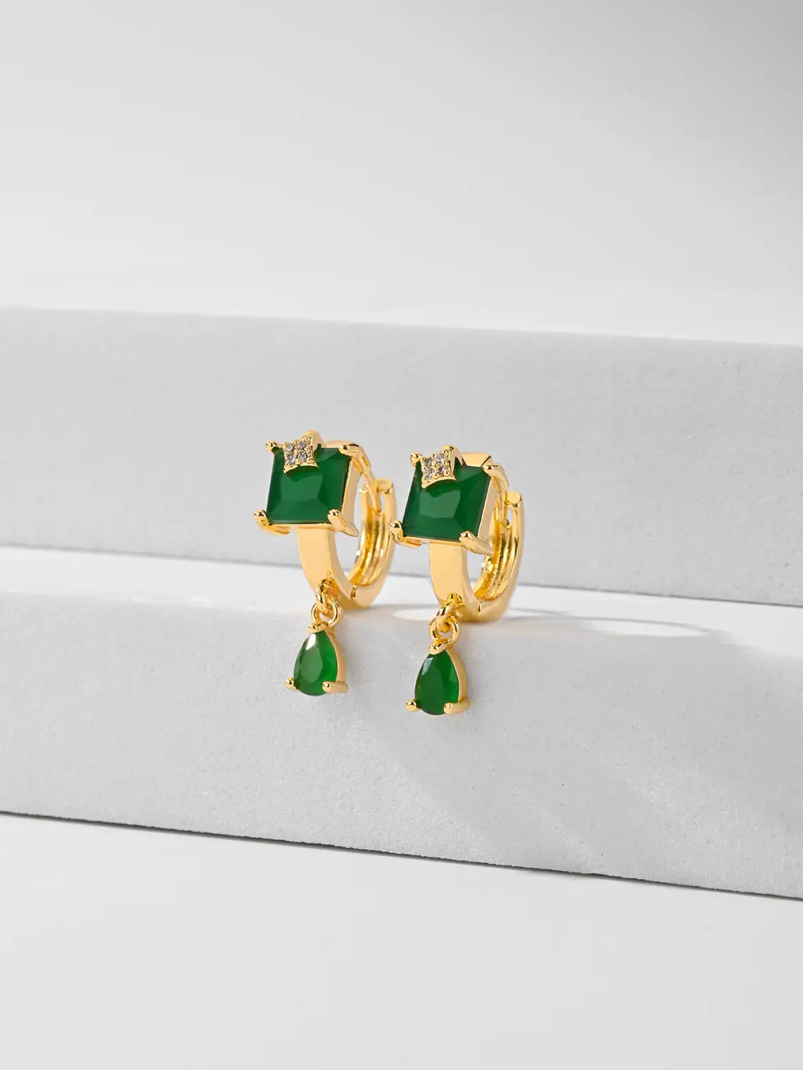 Des boucles d’oreilles créoles goutte en pierre précieuse géométriques élégantes, avec des créoles en or, des pierres vertes à taille carrée, des accents de diamant et des pierres vertes en forme de goutte suspendues.
