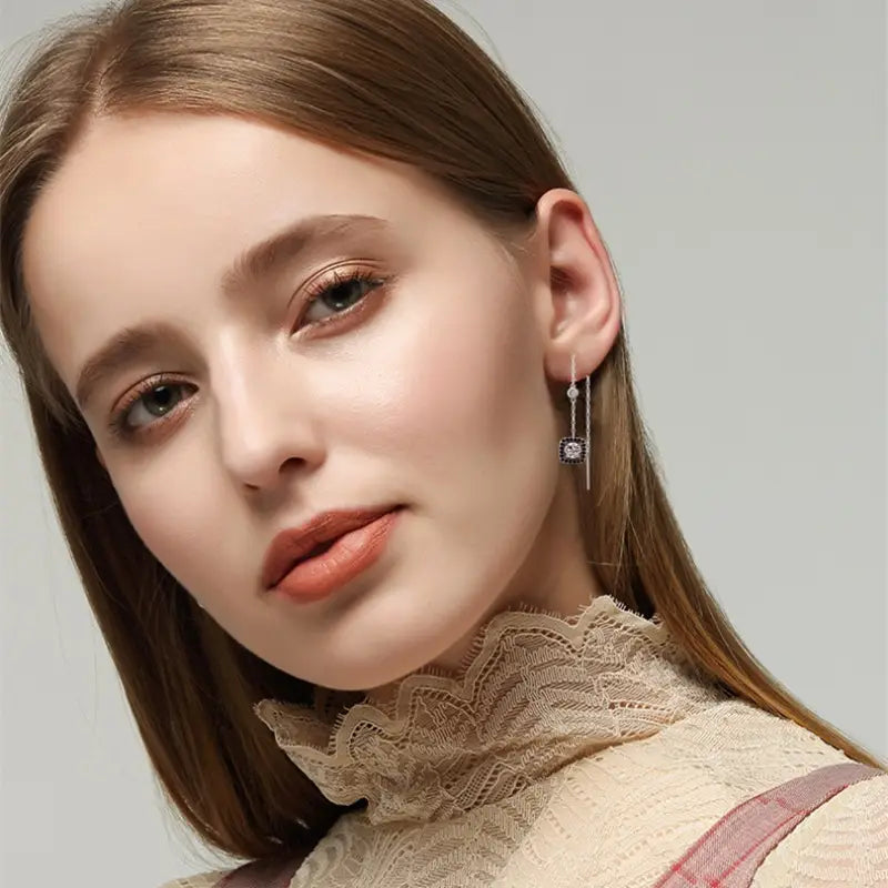 Silver plated zircon square drop earrings feature a delicate chain and square pendant with embedded black gemstones.