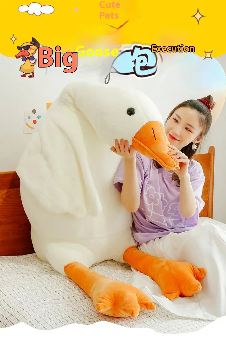Un grand coussin-peluche oie blanche en forme de corps, avec des pattes et un bec orange, fabriqué en matière textile souple.
