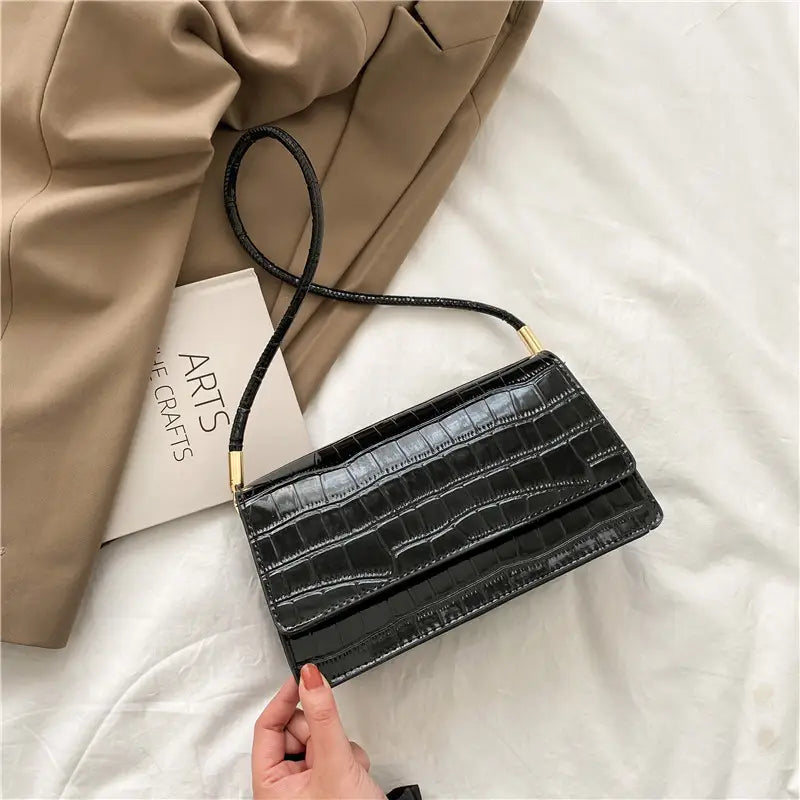 Black crocodile-embossed high-end pu clutch bag with slender shoulder strap and gold-tone hardware designed for underarm use.