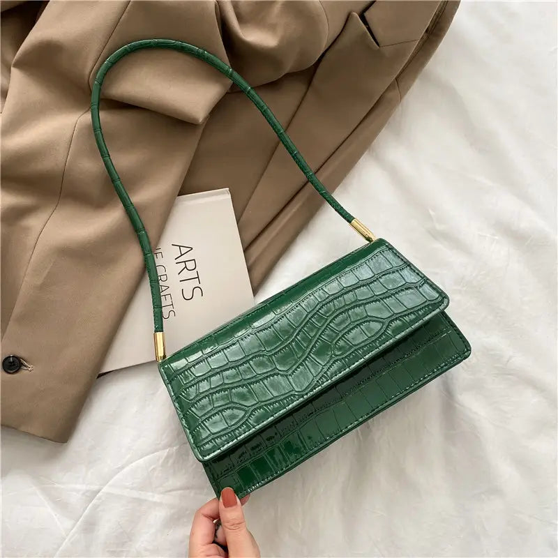 Emerald green croc-embossed mini clutch made of high-end pu with gold-tone hardware and a slender shoulder strap designed as a crocodile pattern underarm bag.