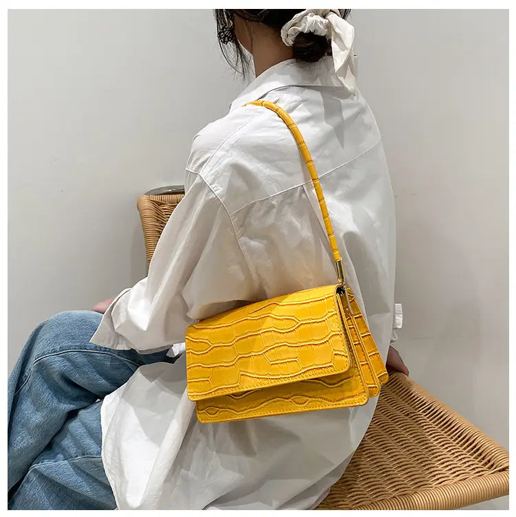 Bright yellow crocodile-textured crossbody bag with matching strap made of high-end PU leather designed as an underarm clutch.