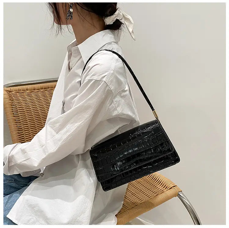 Black crocodile textured underarm bag with a sleek structured design and gold tone hardware made of high end PU clutch material.