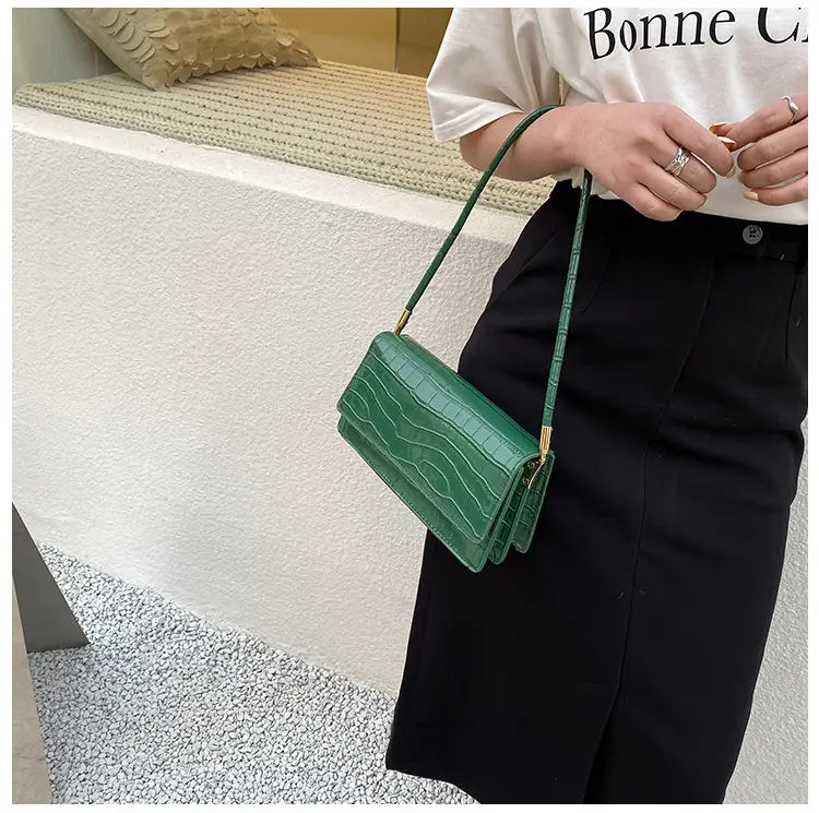 A vibrant green crocodile textured mini crossbody bag made of high-end PU with gold-tone hardware suitable as an underarm clutch.