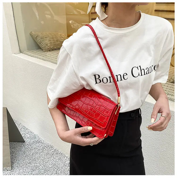 Vibrant red croc emboss leather high-end underarm bag with a slender shoulder strap and crocodile pattern design.