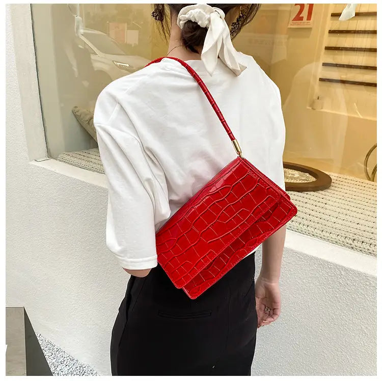 Vibrant red croc-embossed underarm bag made of high-end PU with a sleek glossy finish and gold-tone hardware clutch.