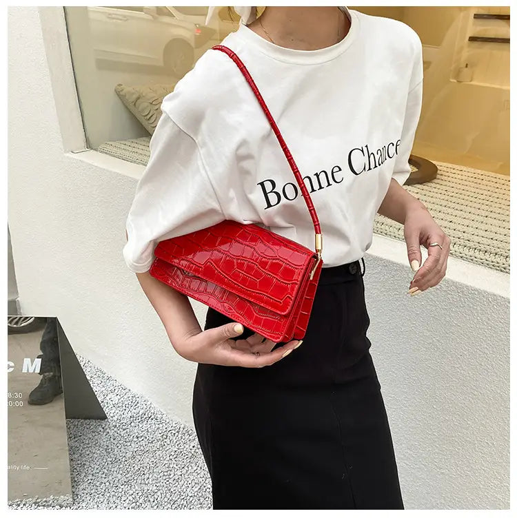 Vibrant red croc-embossed mini crossbody bag with gold-tone hardware made of high-end pu material suitable as a clutch or underarm bag.