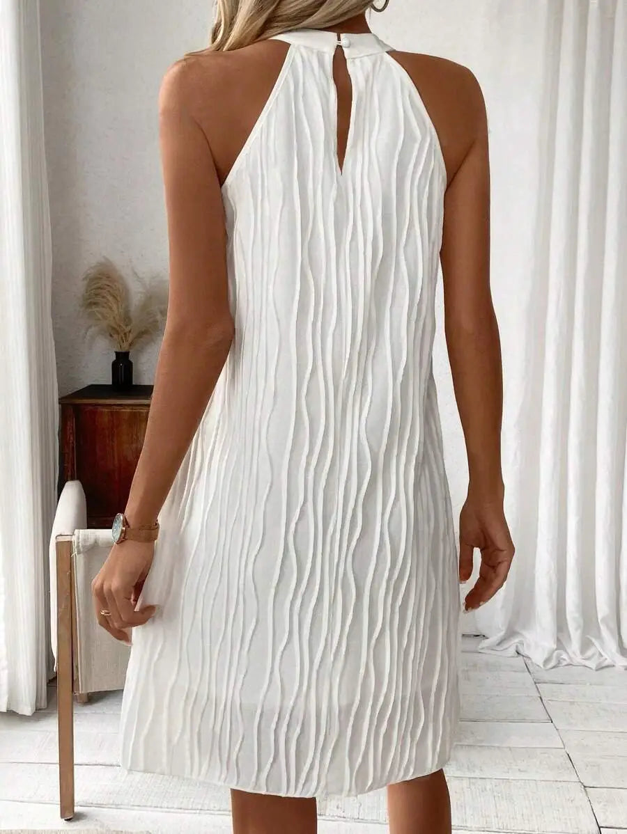 White pleated halter backless dress for women featuring vertical wavy pleats made from lightweight fabric.