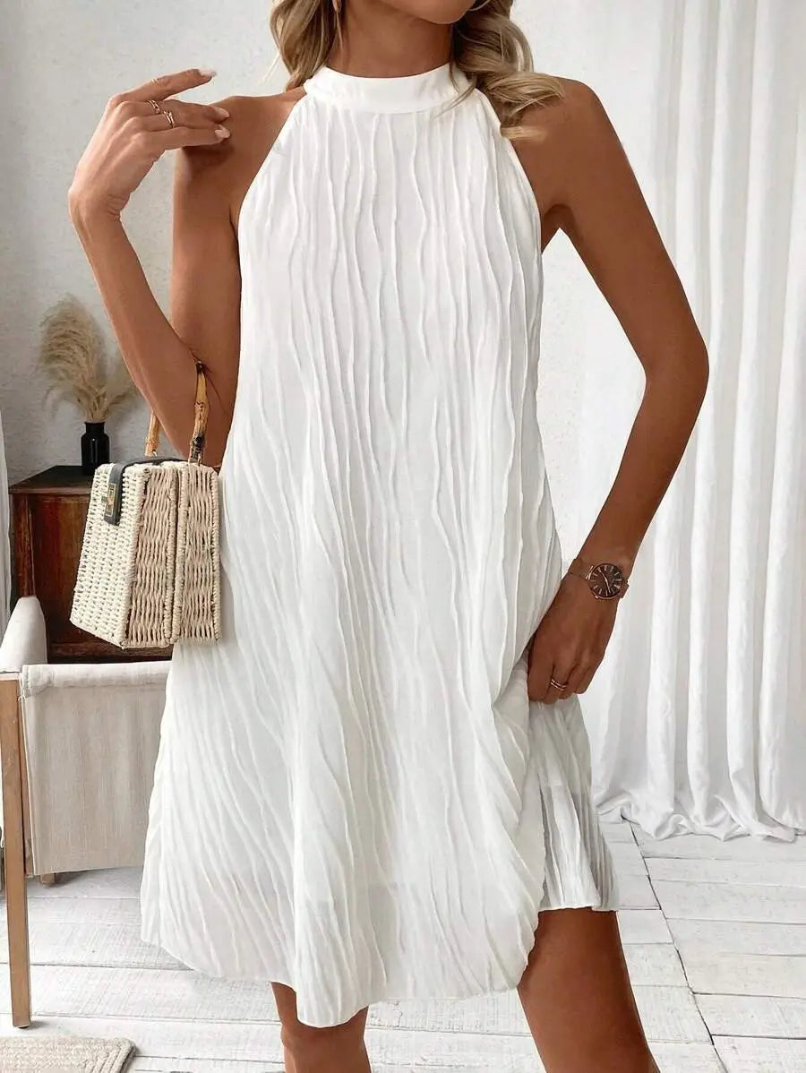 White pleated halter neck dress for women showing the backless design in white fabric.