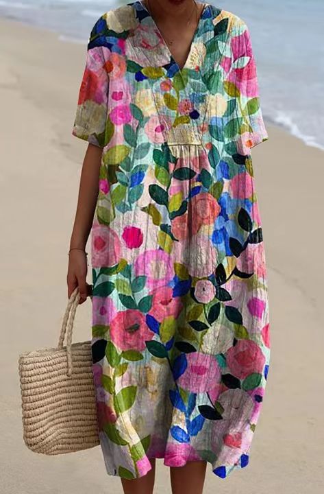 A vibrant floral print v neck loose maxi dress featuring a short-sleeved loose fit with pink blue and green blossoms on a light background fabric.