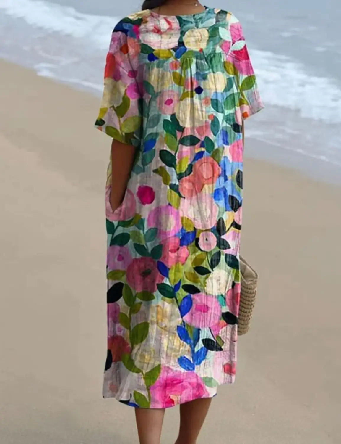 A vibrant floral print v neck loose maxi dress with short sleeves and a gathered neckline in soft pastel tones of pink blue green and yellow.