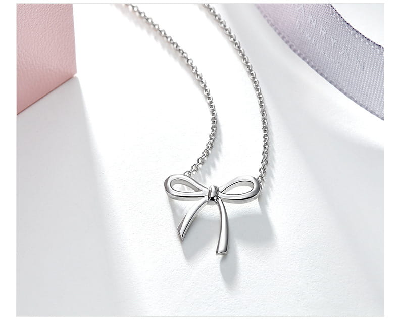 Silver bow-shaped pendant necklace with a delicate chain in Korean style clavicle design featuring gold and silver tones.
