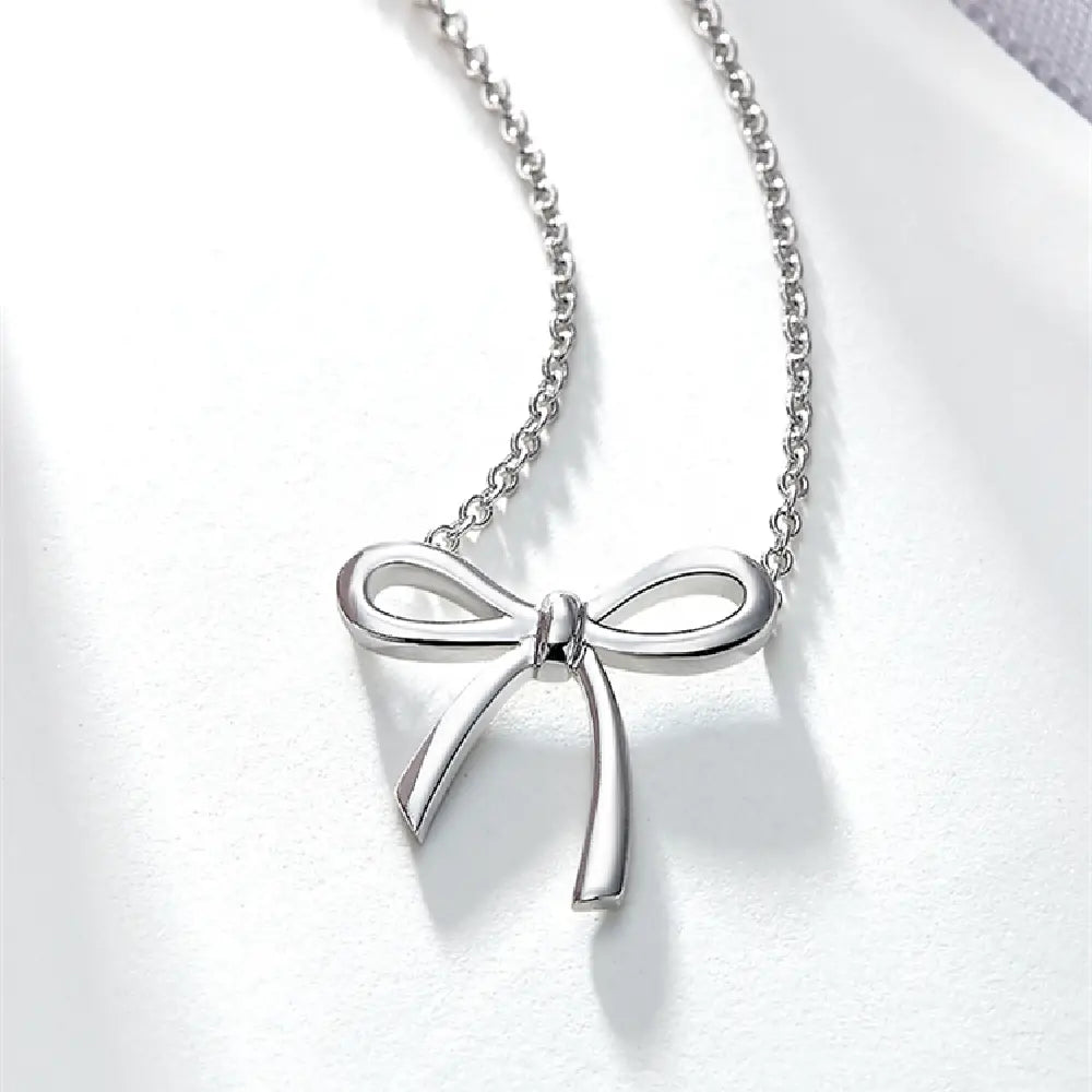 A delicate silver bow-shaped pendant necklace with a fine chain in Korean style clavicle design.
