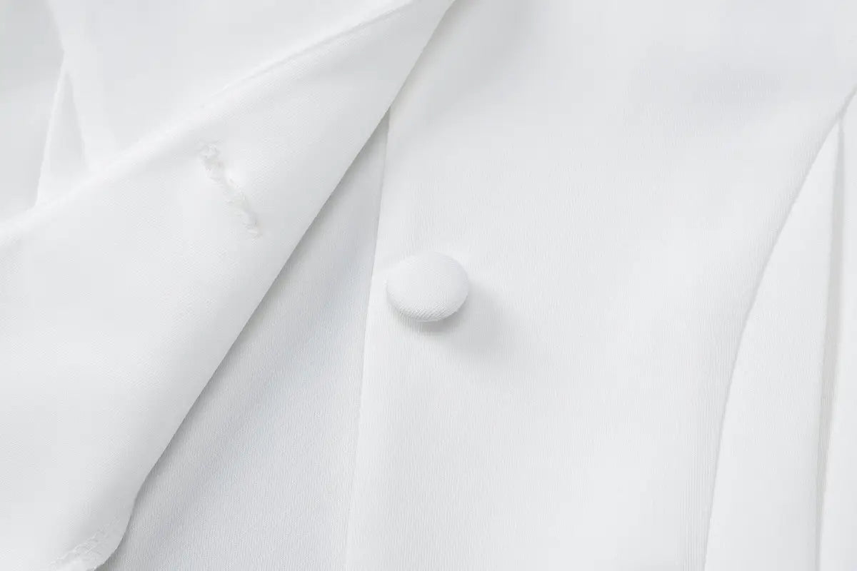 Bouton rond blanc lisse sur un tissu blanc net, pour une robe mini blazer à manches longues et décolleté plongeant en V, avec volants