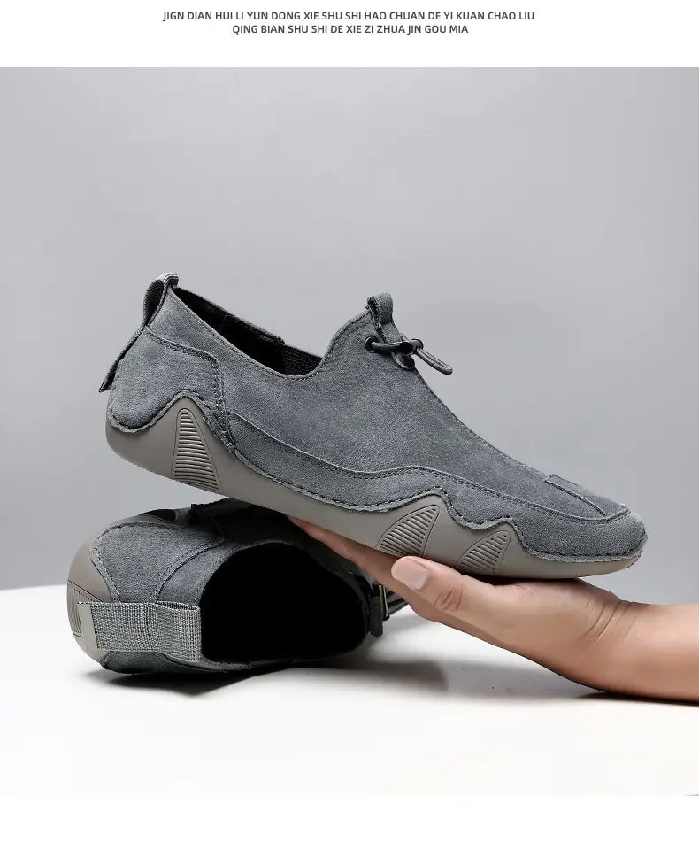 Gray breathable leather loafers with suede slip-on design, textured rubber sole, and adjustable lace detail for casual use.