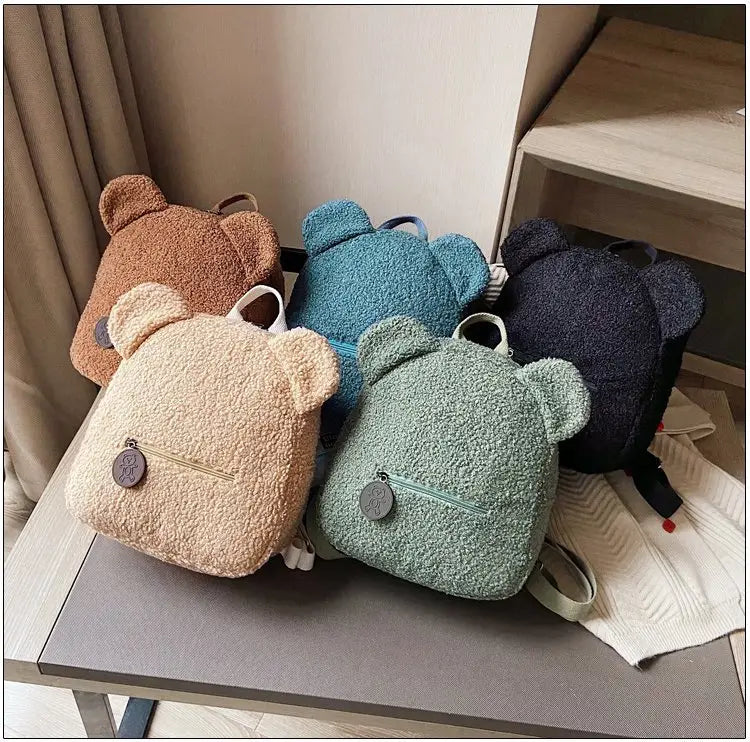 Soft plush teddy bear shaped backpacks in beige teal and navy blue made of fuzzy fleece material for a cute and cozy rucksack.