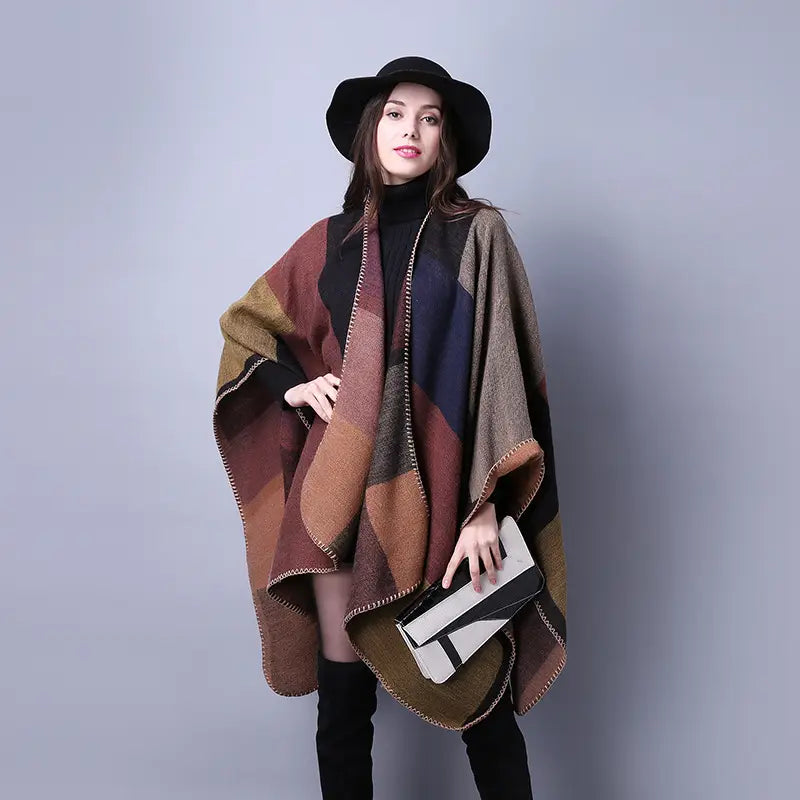 Poncho en laine surdimensionné douillet avec un motif géométrique en patchwork aux tons naturels de brun, rouille et bleu marine, présenté comme face arrière dans une cape en laine à carreaux surdimensionnée, conçue comme étole de voyage géométrique.