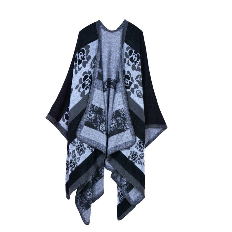 Poncho en maille noir et gris à motif floral, avec un design asymétrique superposé, présenté comme une cape en laine à carreaux surdimensionnée pour voyage géométrique.
