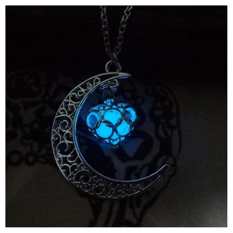 A luminous heart and filigree crescent moon pendant necklace featuring a glowing blue crescent moon with intricate silver filigree detailing and a central luminescent orb.