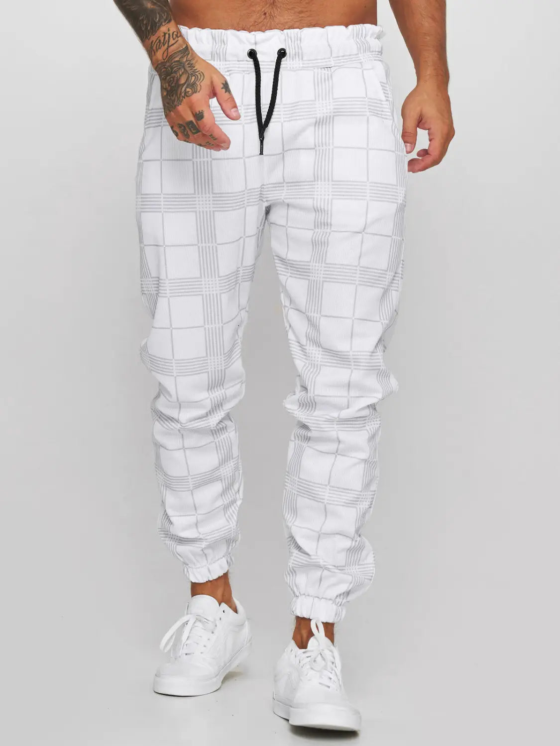 White checkered plaid jogger pants for men featuring a subtle gray pattern and black drawstrings designed for casual wear.