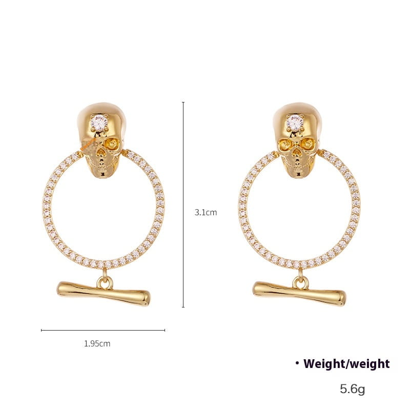 aretes de borla de calavera de oro con calaveras chapadas en oro que presentan cristales centrales, argollas circulares engastadas con diamantes y colgantes en forma de barra con acentos de zirconio