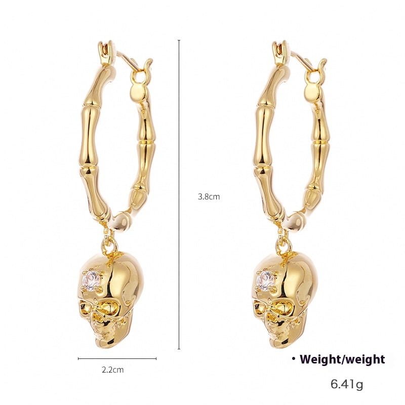 aretes de borla de calavera de oro con un colgante de calavera de color dorado y diseño de aro tipo bambú, con una piedra preciosa de zirconio transparente engastada en la frente