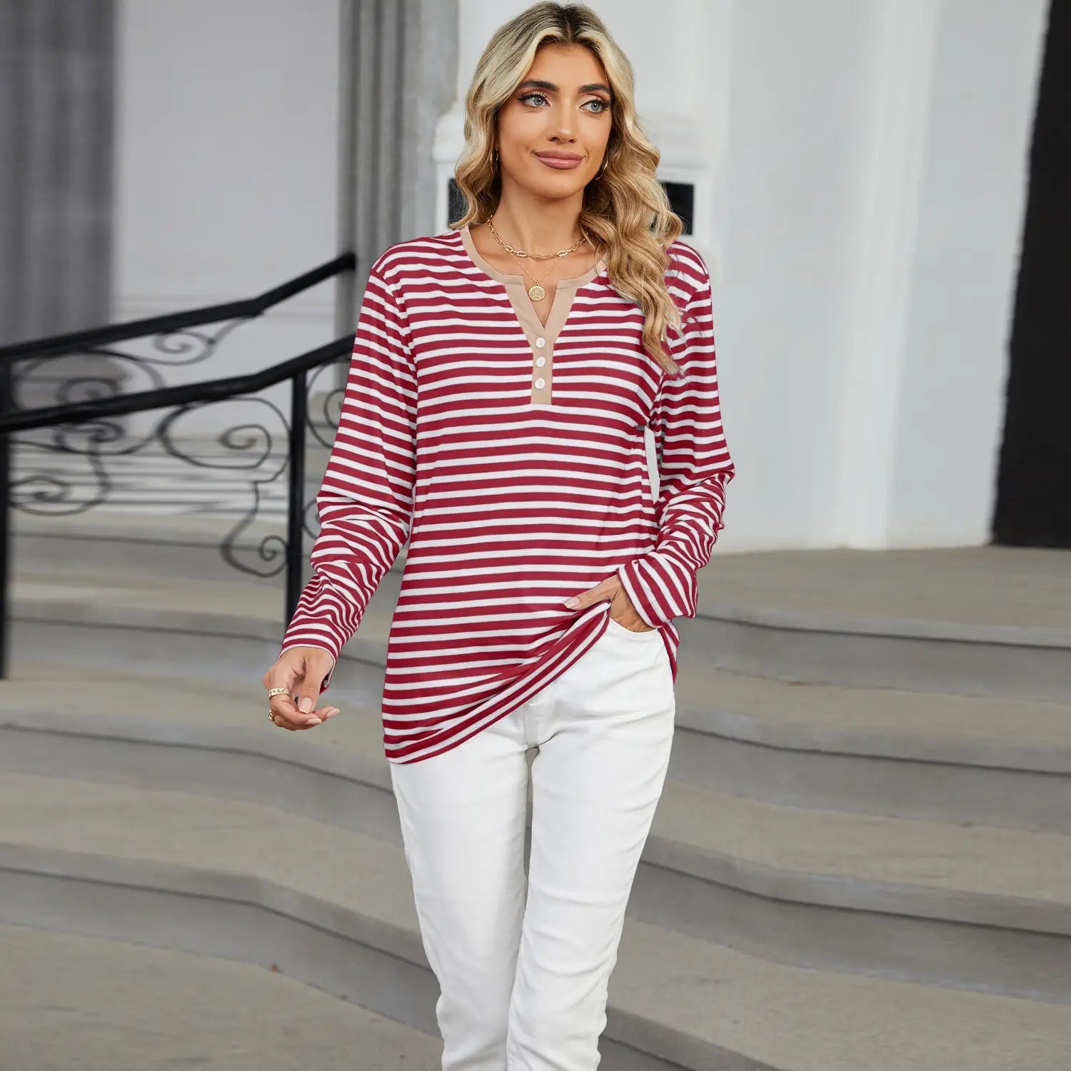 A women’s long-sleeved striped contrast henley v neck t shirt with red and white horizontal stripes, three buttons on the neckline, and a side slit.