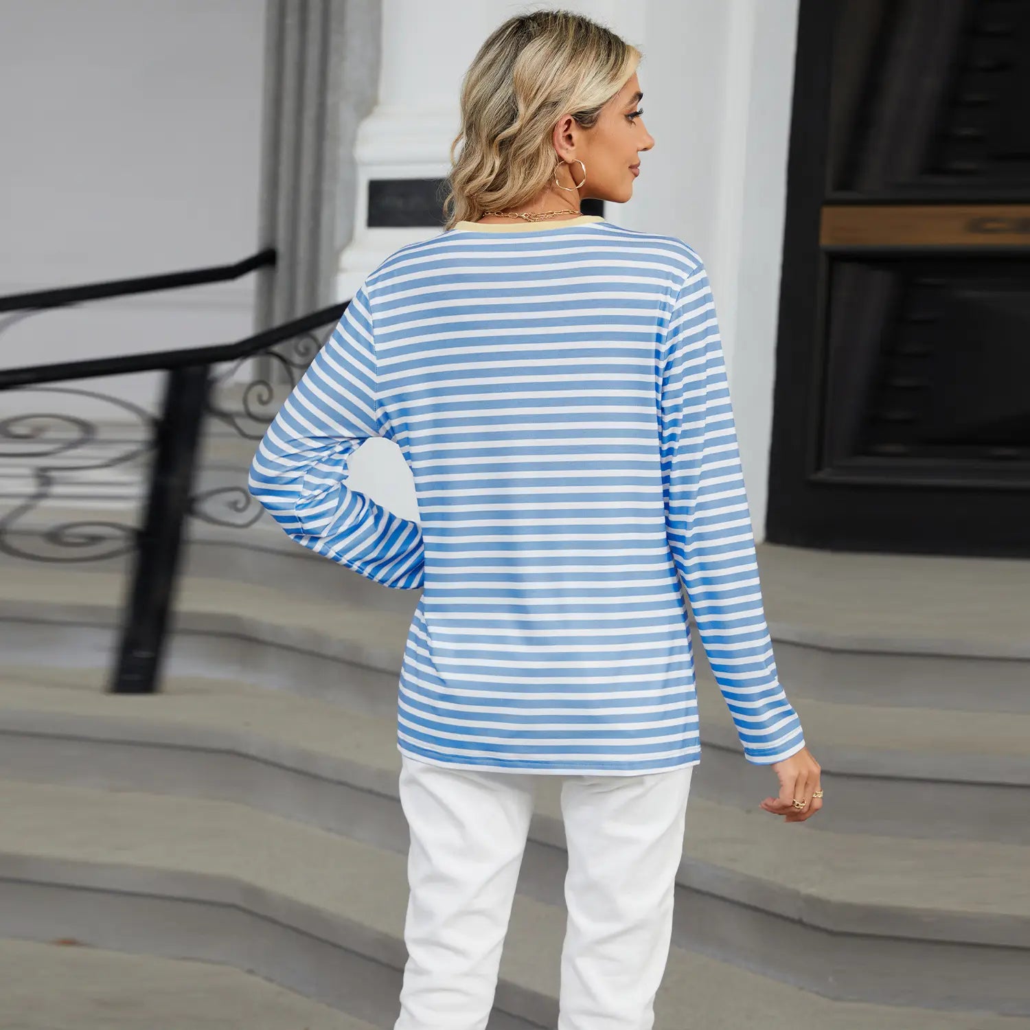 A woman wears a striped contrast Henley long sleeve v neck t shirt featuring light blue and white horizontal stripes.