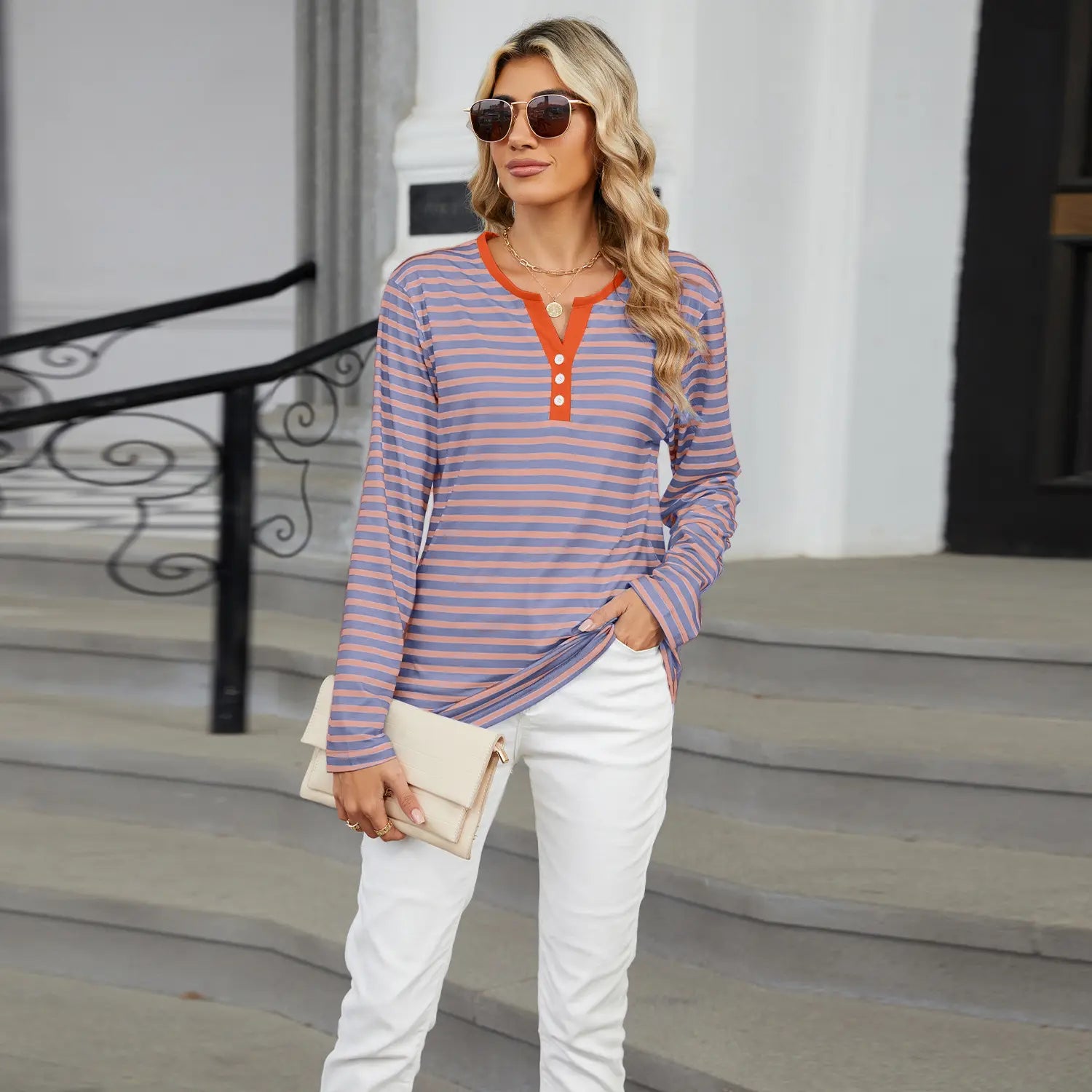 A woman wears a long-sleeved striped contrast henley v neck t shirt in lavender and orange featuring three buttons.