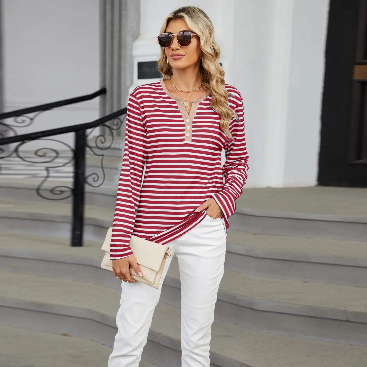 A woman wearing a red and white horizontally striped henley long sleeve v neck t shirt with three buttons at the neckline.