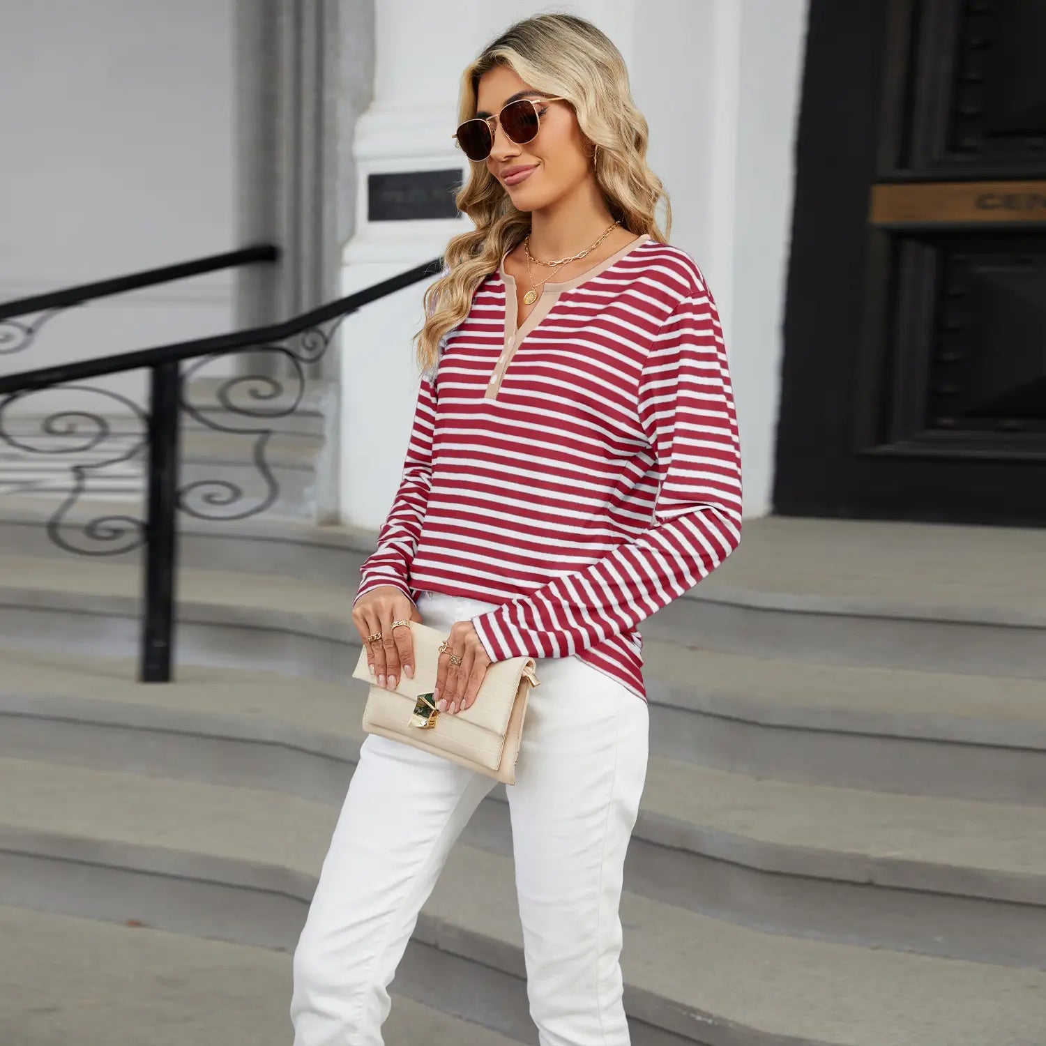 A woman wearing a red and white striped contrast henley long sleeve v neck t shirt made of soft breathable fabric.