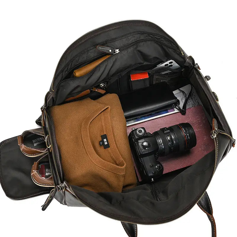 black leather duffel bag vintage large folding travel bag with multiple compartments and zippers containing a camera sweater shoes and other gear