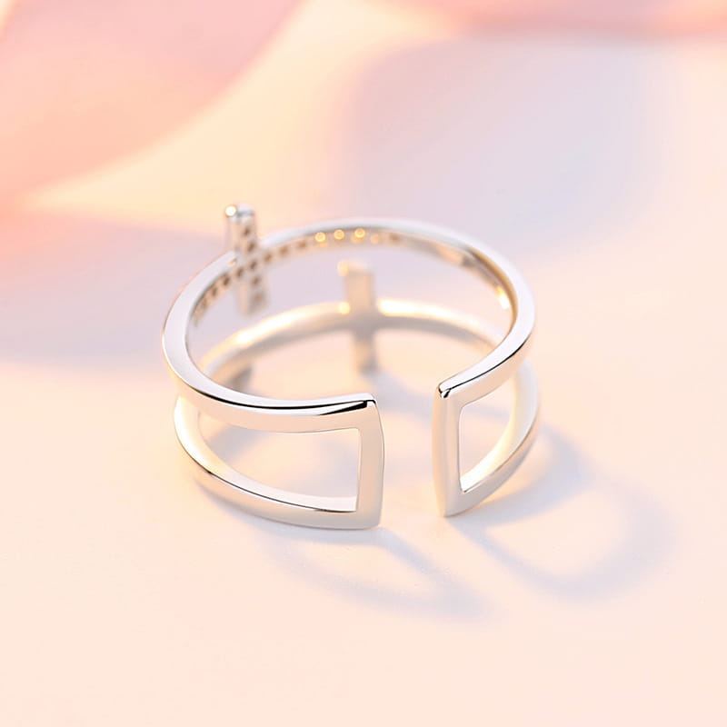 An adjustable double cross zircon inlaid silver ring in a sleek silver tone with a modern geometric design featuring intersecting rectangular bars and small embedded stones.