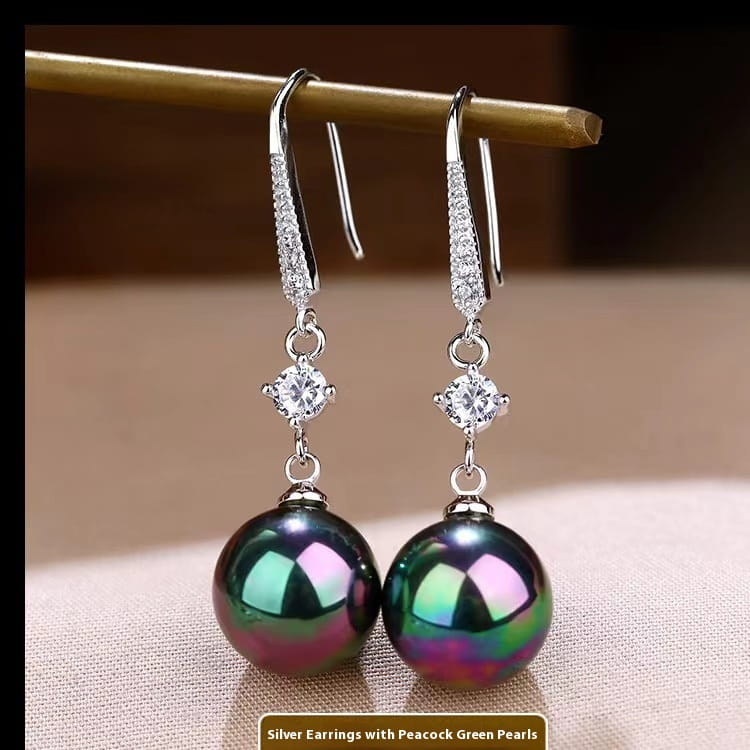 Elegant pearl and pave diamond drop earrings featuring silver dangle hooks with sparkling pave-set details and a single round peacock green pearl with iridescent hues.
