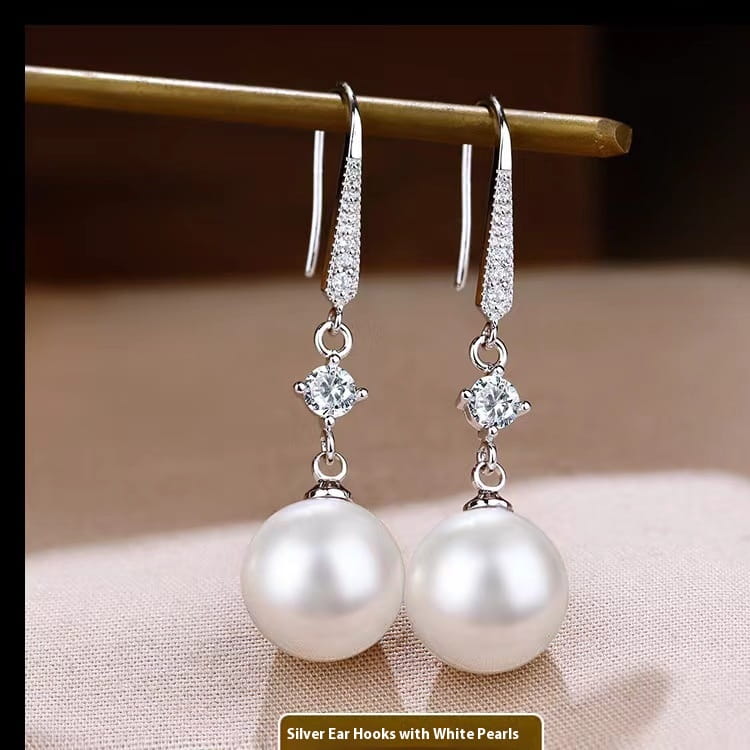 Elegant pearl and pave diamond drop earrings in silver featuring a sparkling pave set hook, a central clear crystal, and a lustrous white pearl drop.