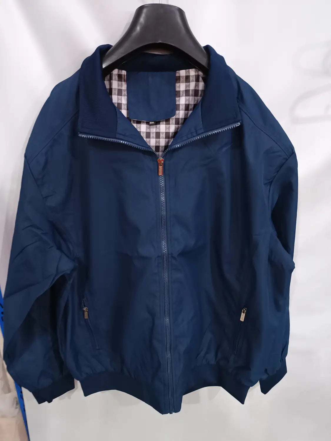 Veste bombardier légère pour homme bleu marine, avec doublure intérieure à carreaux et fermetures éclair argentées, conçue pour un usage décontracté.