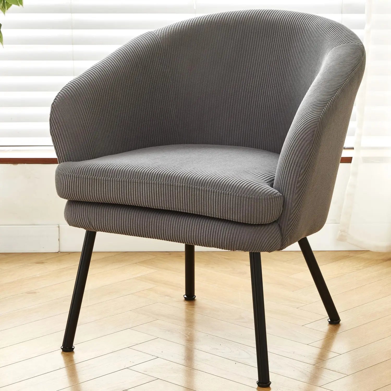 Gray corduroy barrel chair with black metal legs shown from the back side highlighting its textured fabric and sturdy frame.