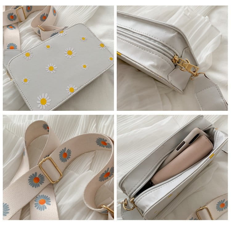 White crossbody bag made of pu leather featuring an embroidered daisy pattern and gold tone hardware with a chain strap.