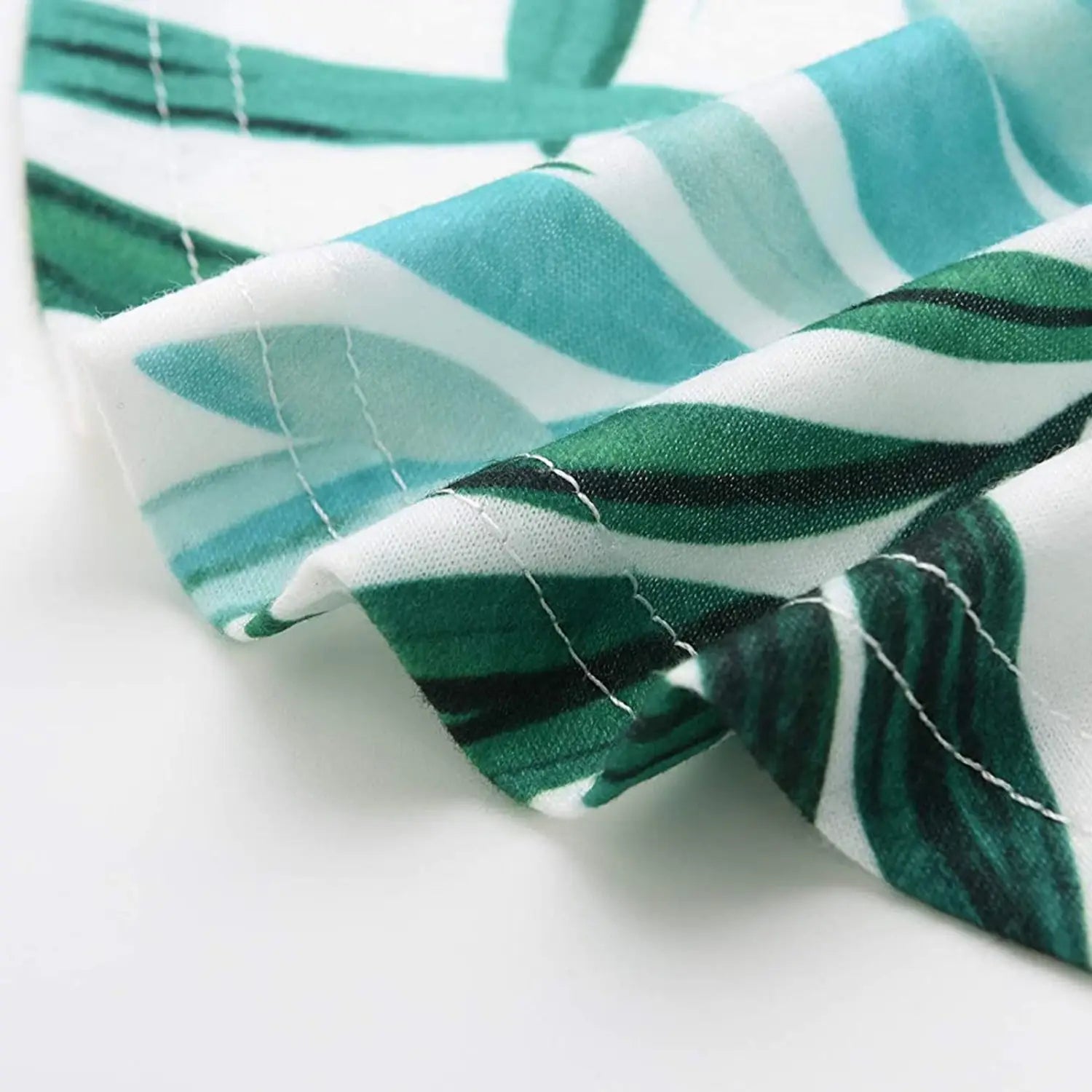 a soft white fabric tropical print sleeveless irregular hem maxi dress featuring vibrant green and teal leaves