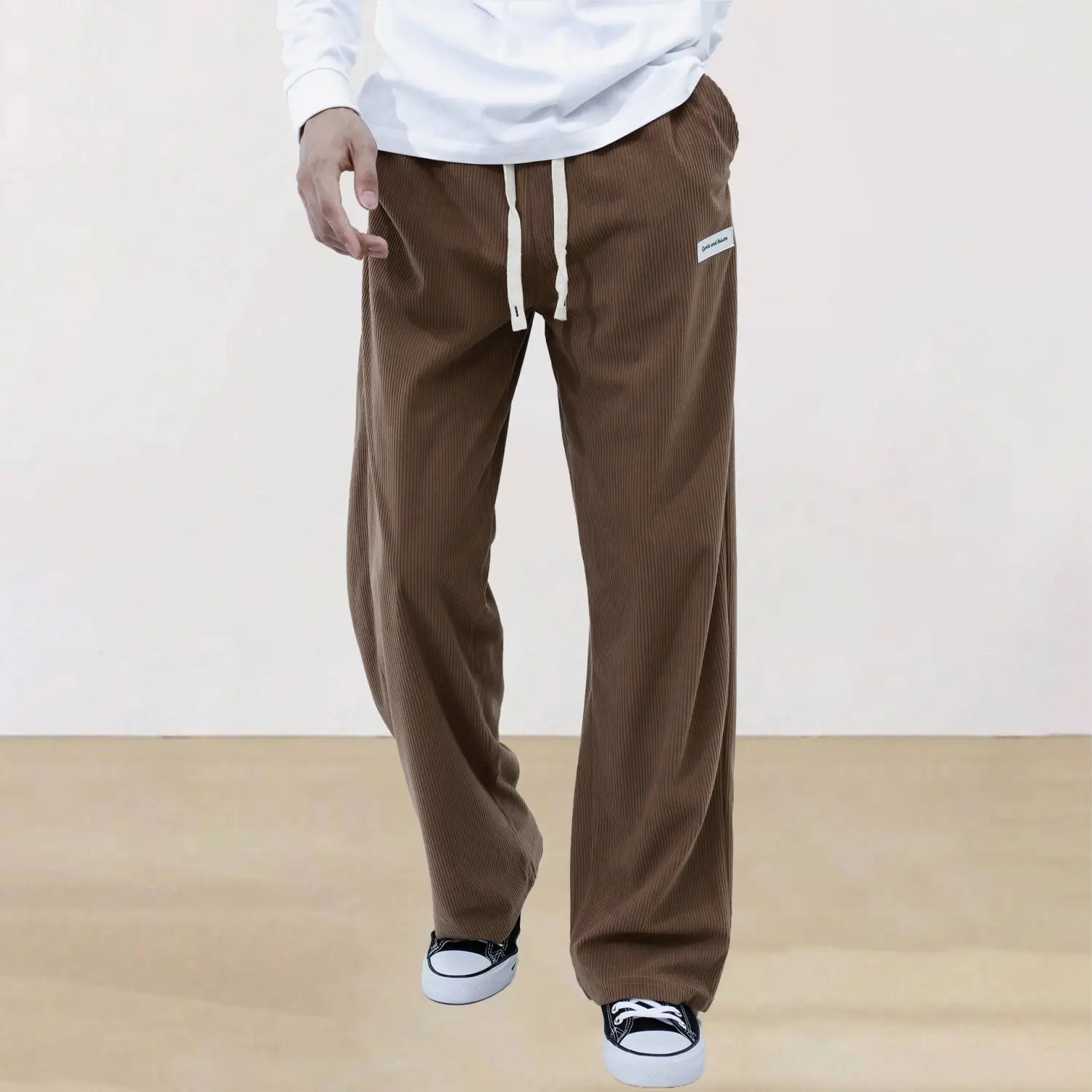 Men’s slim fit brown corduroy sporty drawstring casual trousers with relaxed fit cream-colored drawstrings and a small white label on the thigh.