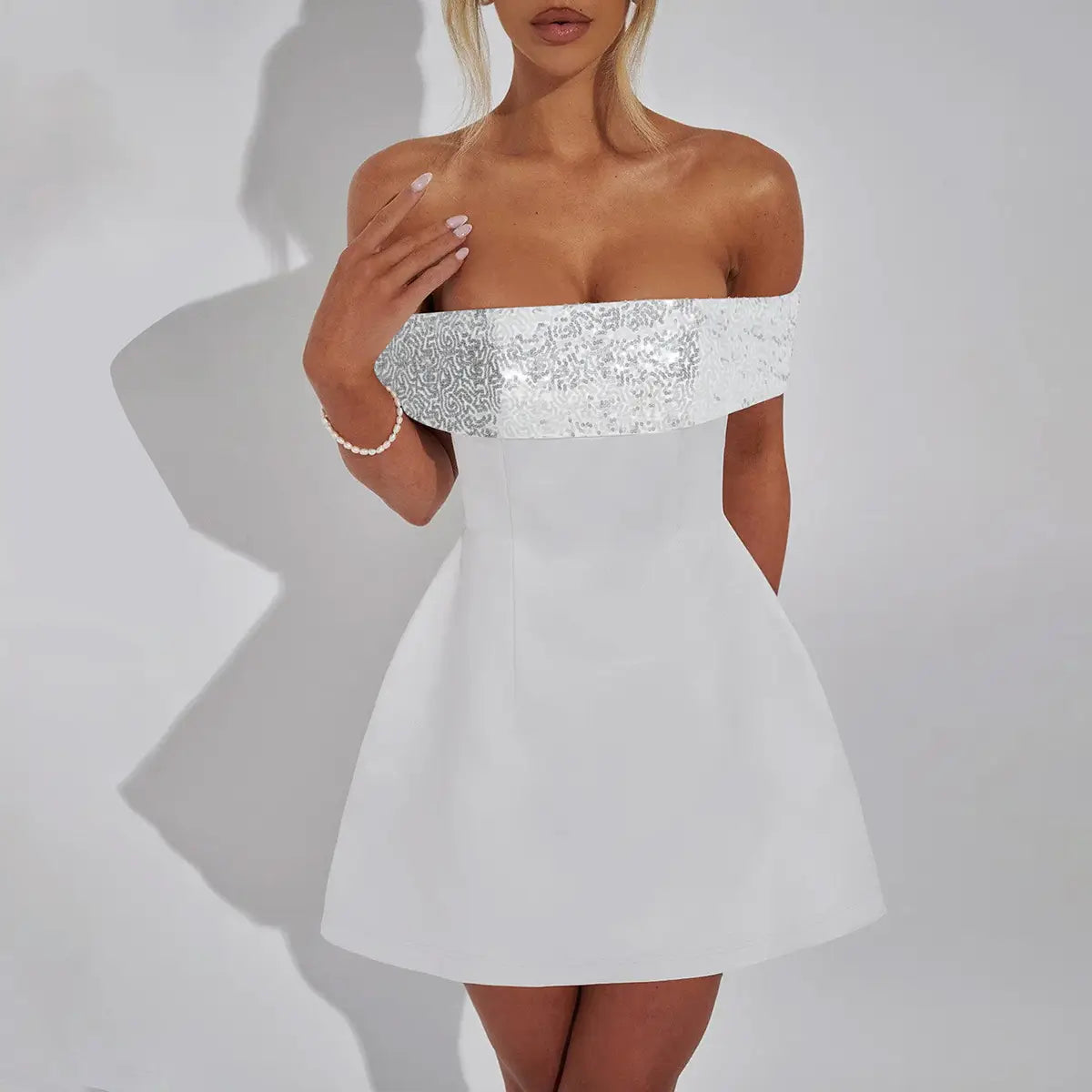White off-the-shoulder bodycon mini dress featuring a sparkling silver sequined band across the bust.