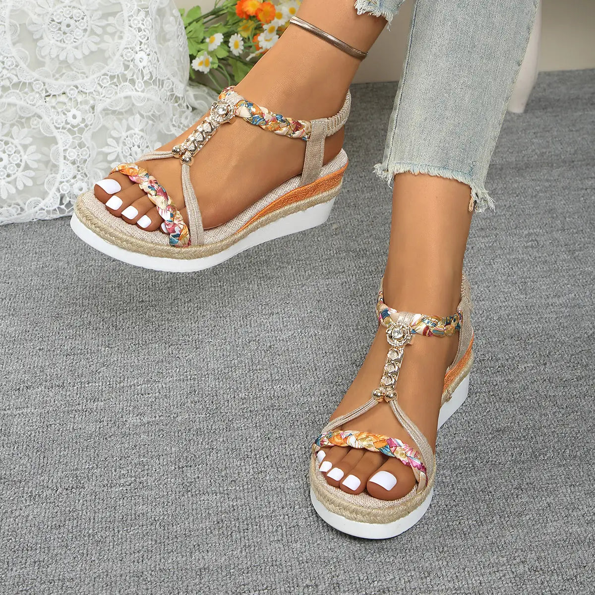 Sandalias tipo cuña beige para mujer con bailarinas tipo espadrille tejidas, con correas trenzadas coloridas y acentos metálicos decorativos.