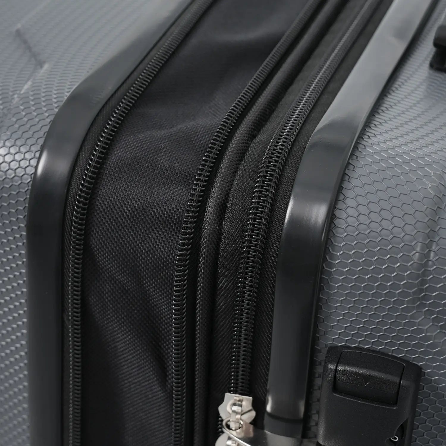 Gray hard-shell 24 inch expandable checked luggage with textured hexagonal pattern black zippers and TSA lock.