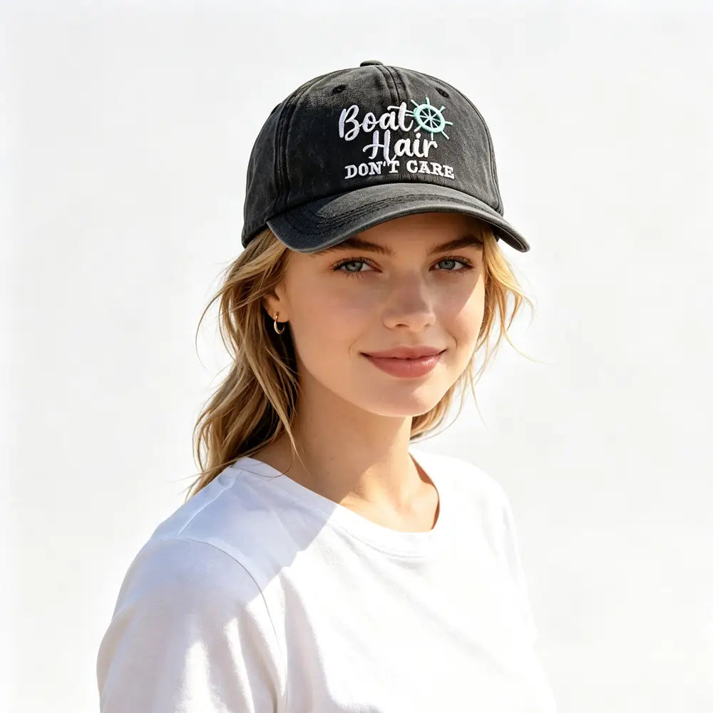 Black baseball cap featuring white embroidered text reading boat hair don’t care and a teal ship’s wheel emblem titled Boat Hair Don’t Care Embroidered Baseball Cap.
