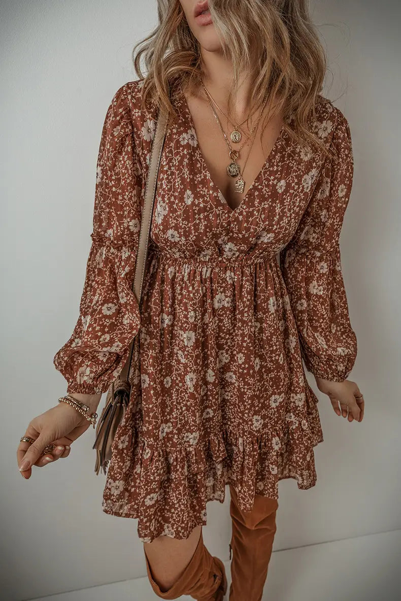 A flowing earth-toned floral bohemian rust mini dress with long puff sleeves and a ruffled hem.