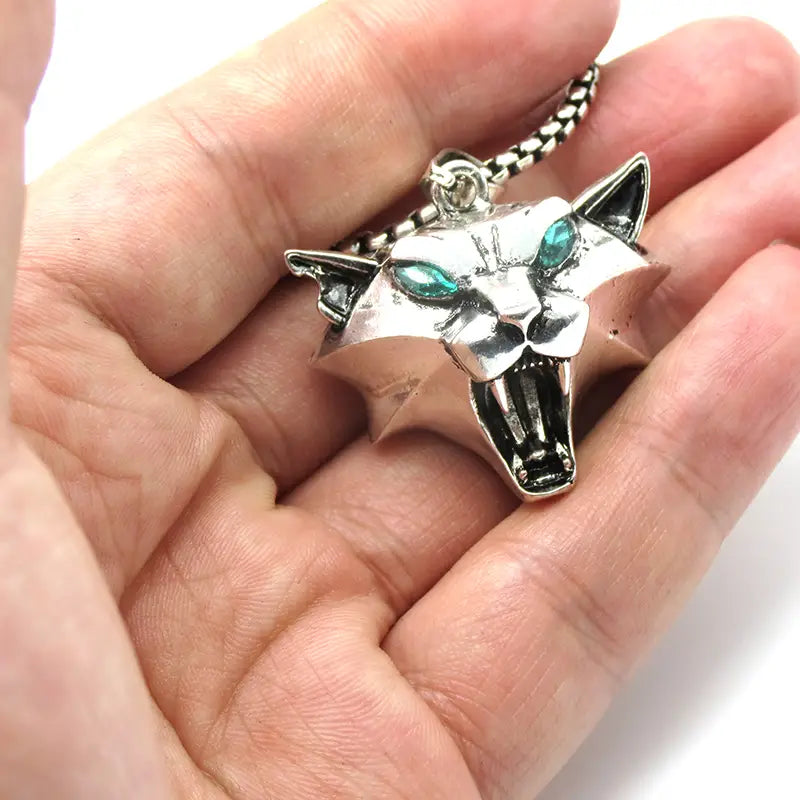 Silver panther pendant chain necklace featuring teal gemstone eyes and a textured chain in a geometric wild game animal design.