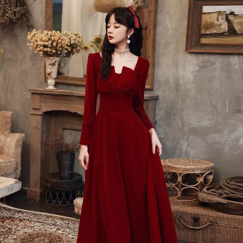 A rich crimson velvet long sleeve a-line gown with a square neckline.