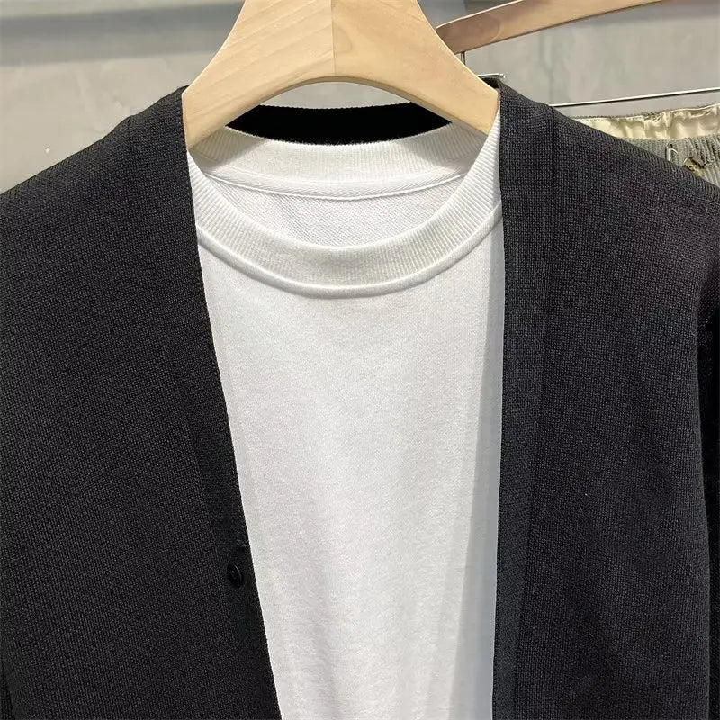 Schwarzer Strickcardigan für Herren aus weicher Wolle, getragen über einem weißen gerippten Rundhals-T-Shirt für lässige Layering-Looks.
