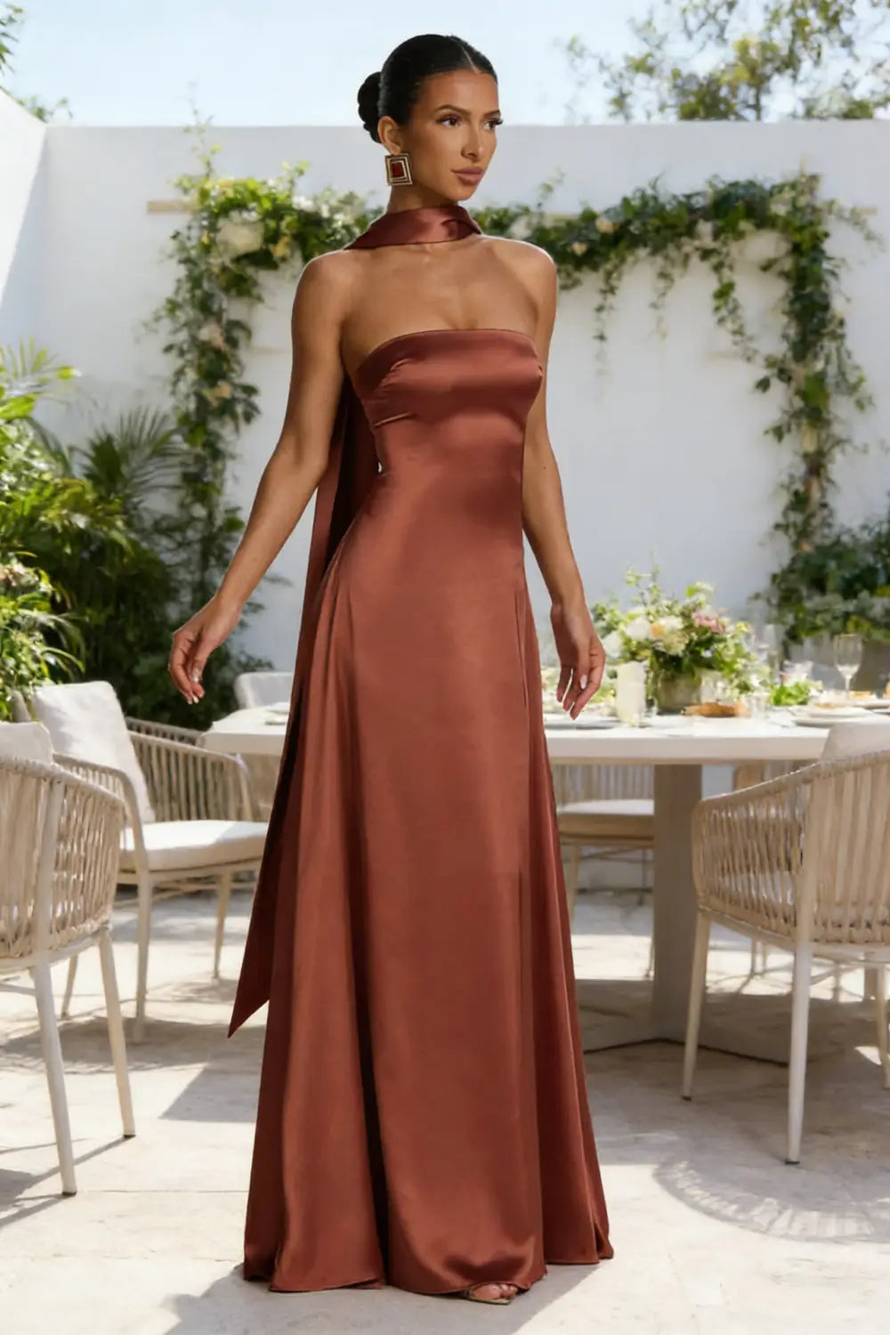 Un vestido de noche de satén fluido sin tirantes y en color óxido, con escote drapeado y una cola larga.